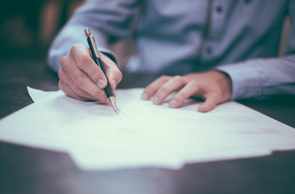 man writing with a black and gold pen