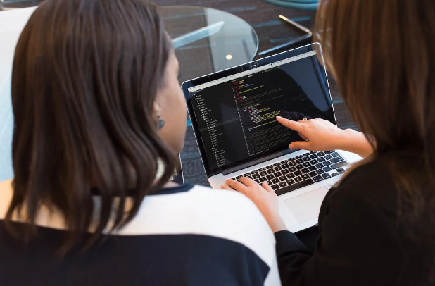 two women looking at a code on laptop