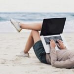 man using laptop at a beach