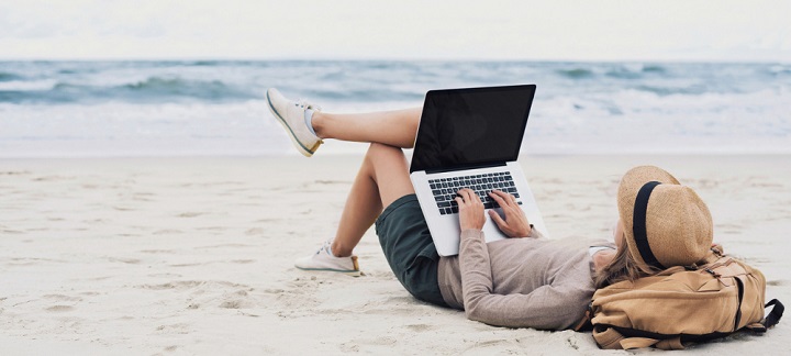 Woman at a beach working on laptop
